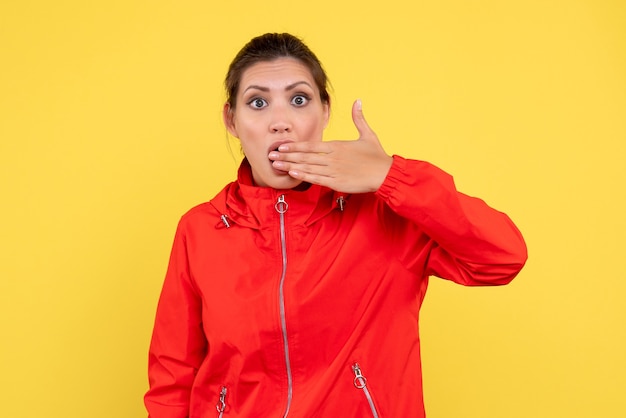 Front view young female in red coat on yellow background