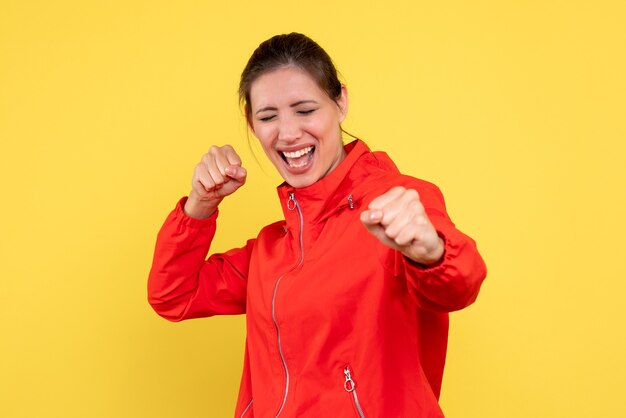 Front view young female in red coat on yellow background