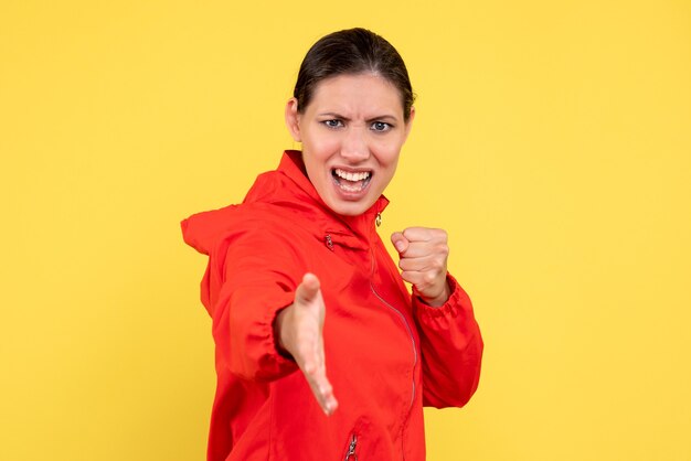 Front view young female in red coat on yellow background