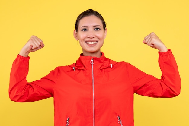 Front view young female in red coat on yellow background