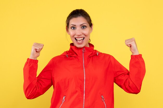 Front view young female in red coat on yellow background