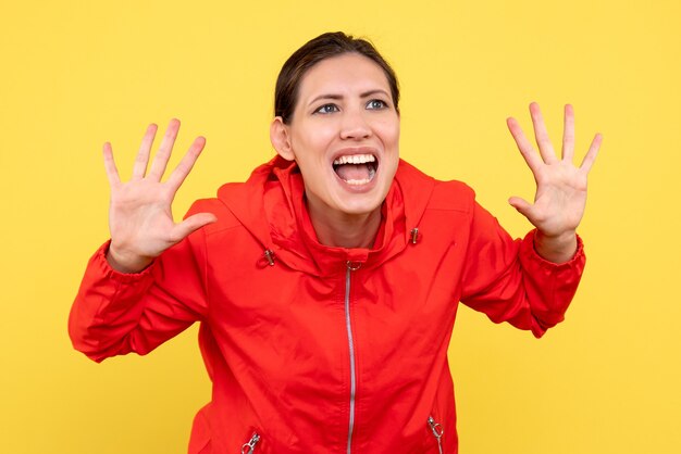 Front view young female in red coat on yellow background