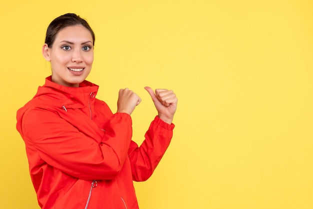 Front view young female in red coat on yellow background