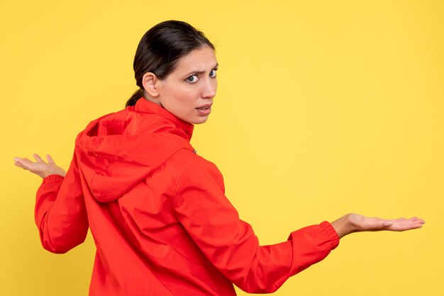 Front view young female in red coat on yellow background