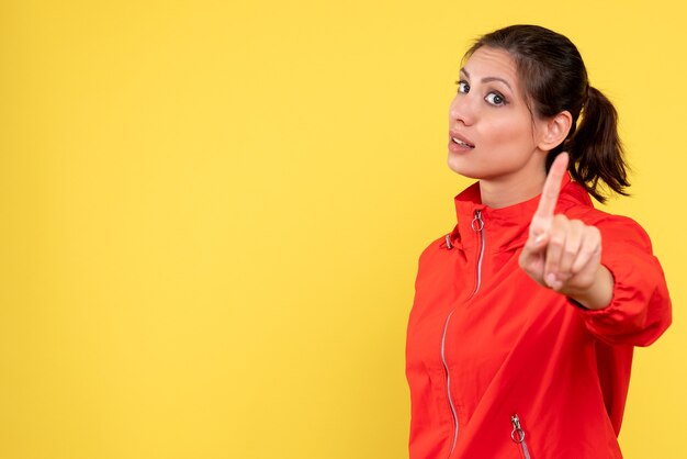 Front view young female in red coat on yellow background