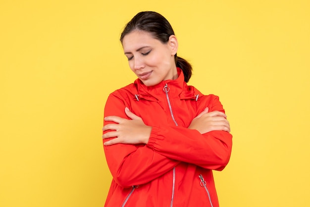 Vista frontale giovane donna in cappotto rosso su sfondo giallo