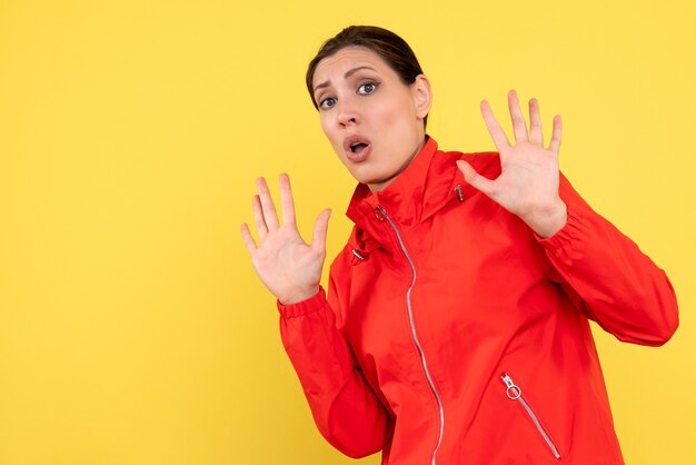 Front view young female in red coat on yellow background