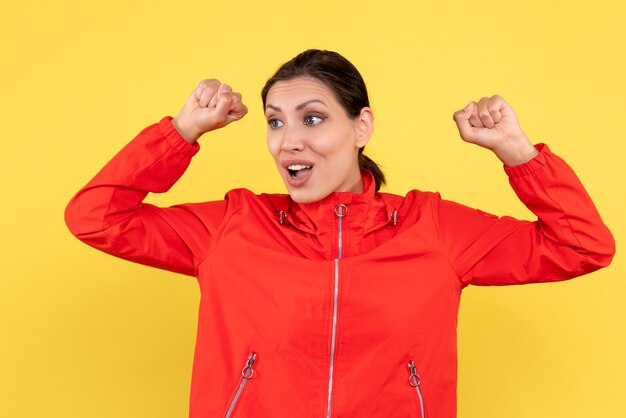 Front view young female in red coat on yellow background