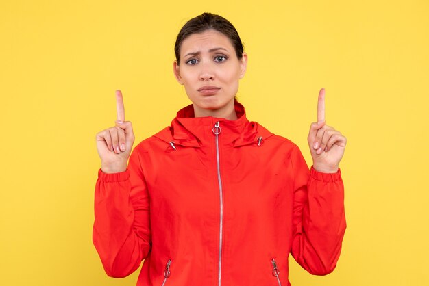 Vista frontale giovane donna in cappotto rosso su sfondo giallo