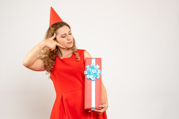 Вид спереди молодая женщина в красном платье празднует рождество с подарком