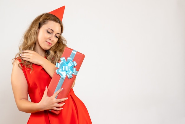 Вид спереди молодая женщина в красном платье празднует рождество с подарком