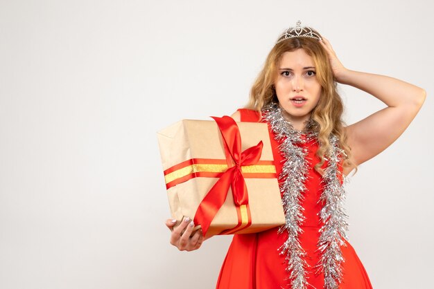 クリスマスプレゼントを保持している赤いドレスの若い女性の正面図
