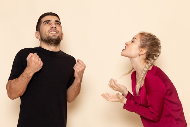 Front view young female in red shirt quarelling with male on the cream space female cloth  photo