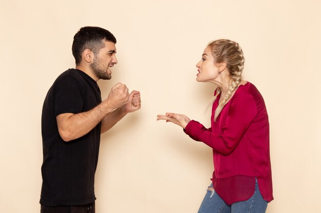 Front view young female in red shirt quarelling with young man on the cream space female cloth  quarell