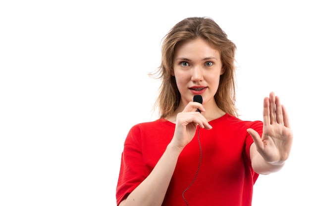 A front view young female in red shirt talking through microphone on the white