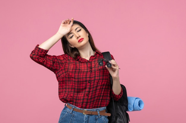 Foto gratuita giovane femmina di vista frontale in camicia rossa con il binocolo sulla donna di modo di colore di sfondo rosa