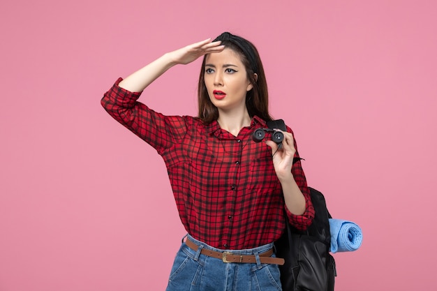 Front view young female in red shirt with binoculars on pink background color woman student