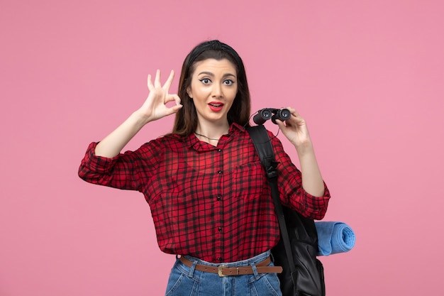 Front view young female in red shirt with binoculars on a pink background fashion color woman