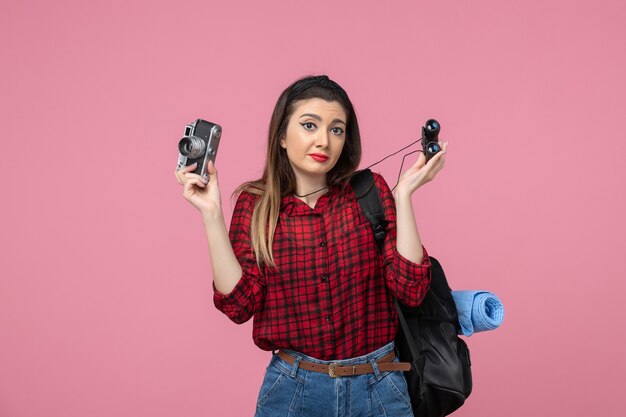 Front view young female in red shirt with binoculars on a pink background human color woman