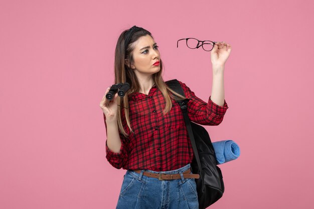 Front view young female in red shirt with binoculars on a pink background woman photo model