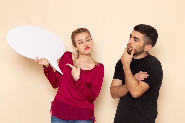 Front view young female in red shirt with male holding white sign on the cream space female cloth  photo