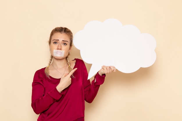 Free photo front view young female in red shirt with tied mouth holding huge white sign on the light space violence beating domestic