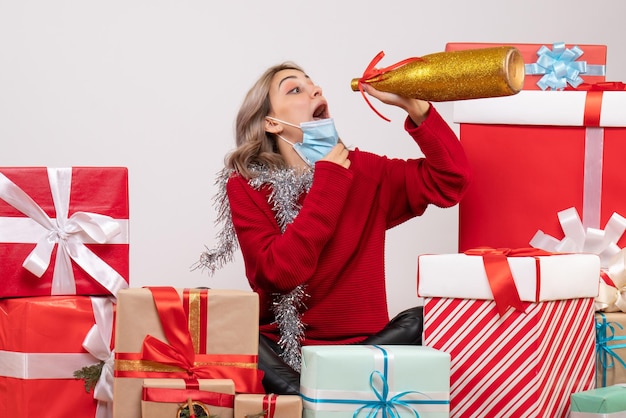 Front view young female sitting around christmas presents drinking champagne