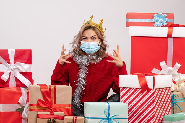 Front view young female sitting around christmas presents in mask