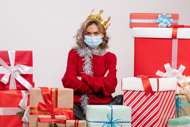 Front view young female sitting around christmas presents in mask