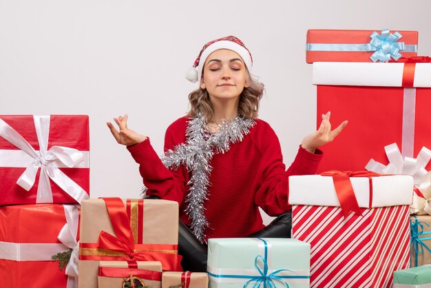 Front view young female sitting around christmas presents meditating