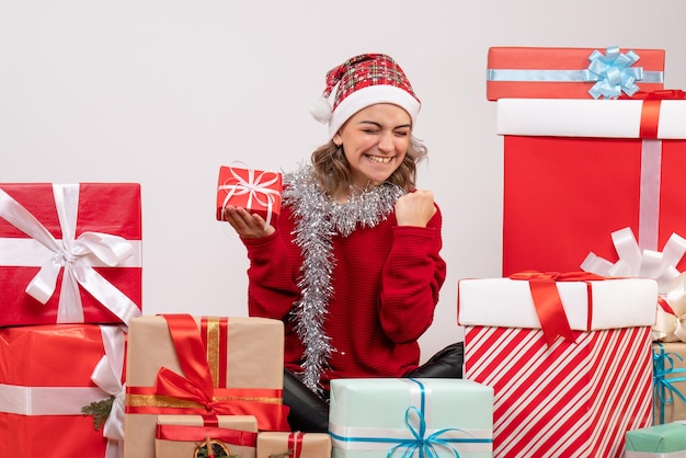 Front view young female sitting around christmas presents and rejoicing