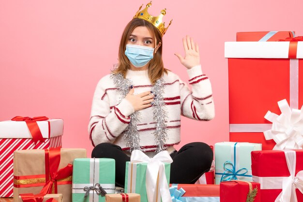 Front view young female sitting around christmas presents in sterile mask