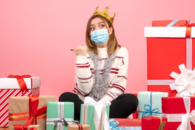 Free photo front view young female sitting around christmas presents in sterile mask