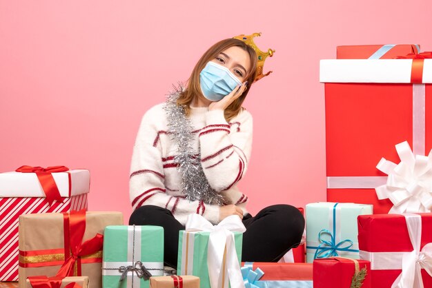 Front view young female sitting around christmas presents in sterile mask