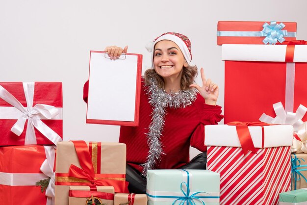 Front view young female sitting around christmas presents with note