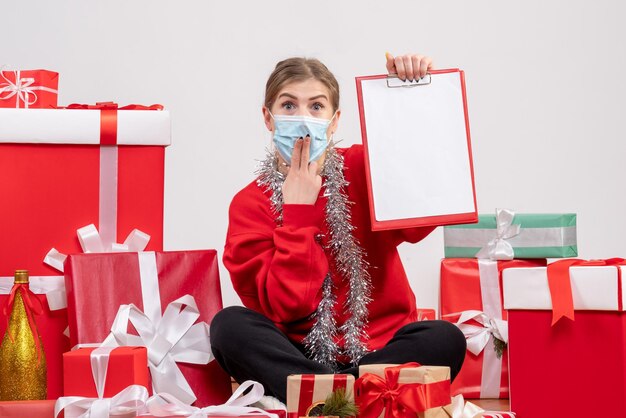 クリスマスプレゼントの周りに座っている正面図若い女性