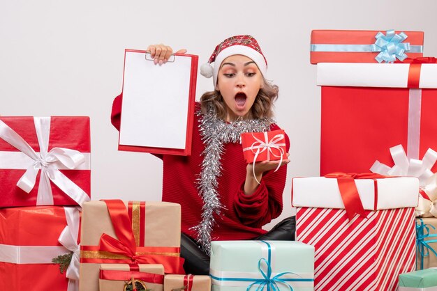 Front view young female sitting around christmas presents with note