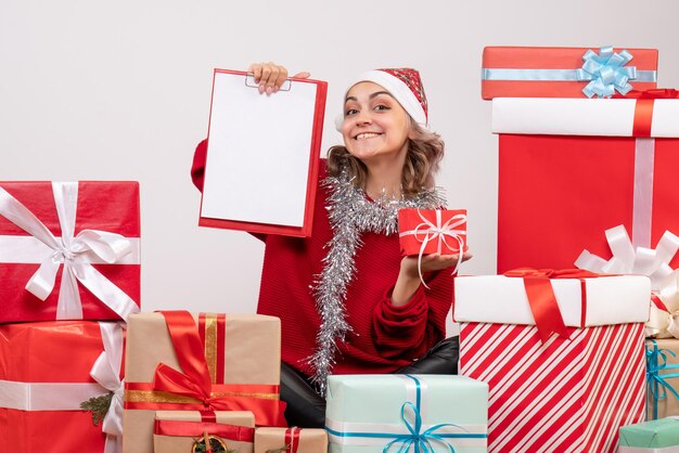 Front view young female sitting around christmas presents with note