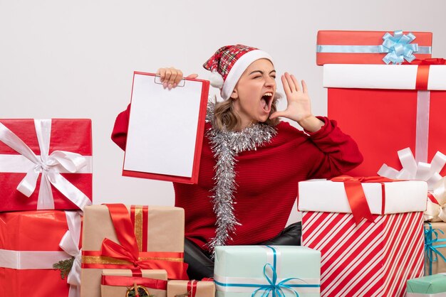 Front view young female sitting around christmas presents with note