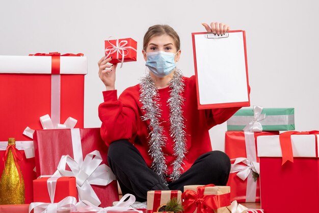 Front view young female sitting around christmas presents with note