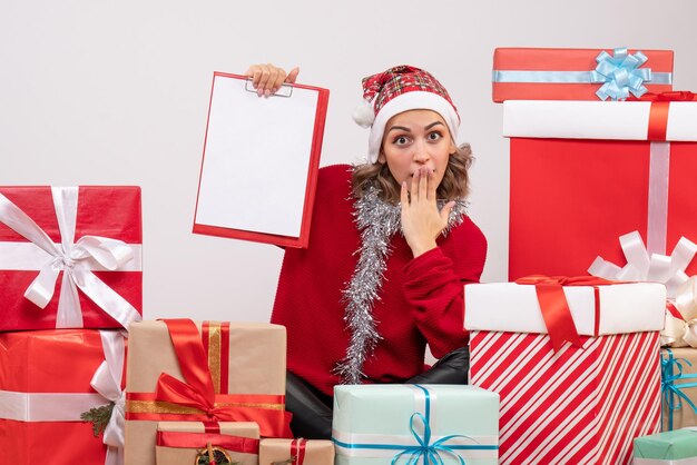 Front view young female sitting around christmas presents with note