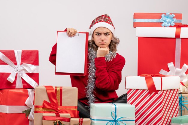Front view young female sitting around christmas presents with note