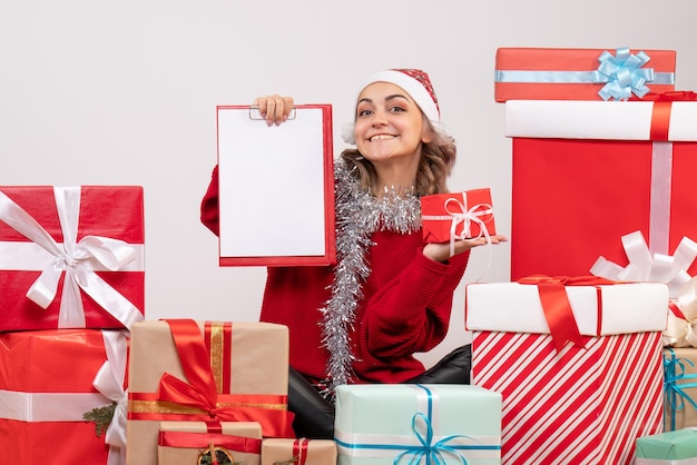 Free photo front view young female sitting around christmas presents with note