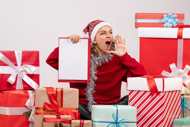 Front view young female sitting around christmas presents with note