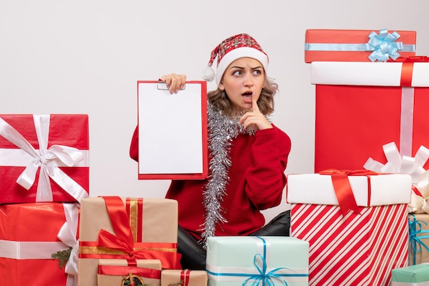 Front view young female sitting around christmas presents