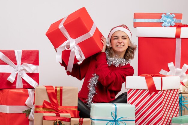 Вид спереди молодая женщина, сидящая вокруг рождественских подарков