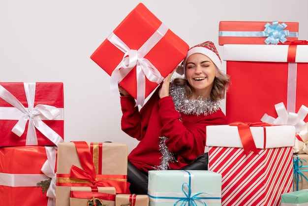 Вид спереди молодая женщина, сидящая вокруг рождественских подарков
