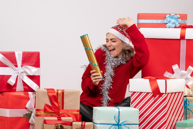 Front view young female sitting around christmas presents