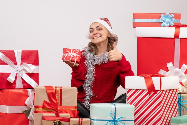 クリスマスプレゼントの周りに座っている正面図若い女性