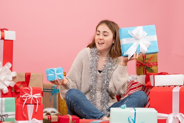 さまざまなプレゼントの周りに座っている正面図若い女性